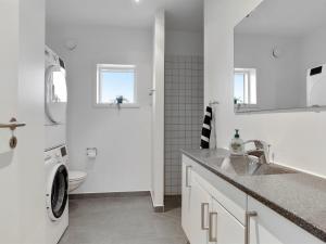 a white bathroom with a sink and a washing machine at Holiday Home Gerniot - 500m from the sea by Interhome in Frederikshavn