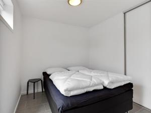 a bed with white sheets on it in a room at Holiday Home Gerniot - 500m from the sea by Interhome in Frederikshavn