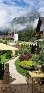 a garden with a table and an umbrella and a mountain at Pensiunea Turistica Villa Ermitage in Buşteni