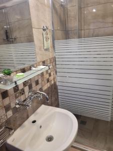 ein Bad mit einem Waschbecken und einer Dusche in der Unterkunft Къща за гости Феникс in Kopriwschtiza