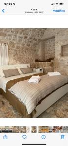 a bedroom with two beds and a stone wall at Masseria I Raffi b&b in Monopoli