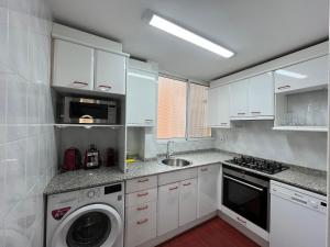 a kitchen with white cabinets and a washer and dryer at August centro Tarragona in Tarragona