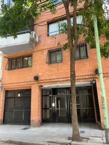 un edificio de ladrillo con puertas abiertas junto a un árbol en Acogedor departamento en Caballito en Buenos Aires