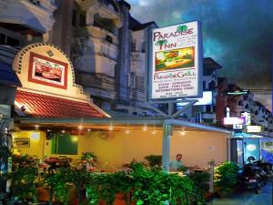 a man sitting at a restaurant with a sign at Paradise Inn in Karon Beach