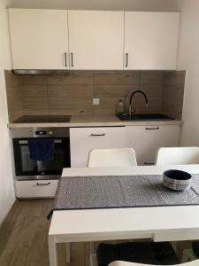 uma cozinha com armários brancos, um lavatório e uma mesa em Ferienwohnung Möwennest em Elmenhorst