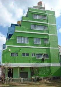 un edificio verde con ventanas blancas en un lateral en Guest House Green House, en Naha