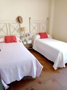 a bedroom with two beds with white sheets and red pillows at Costa Ballena Torresalada 1 in Costa Ballena