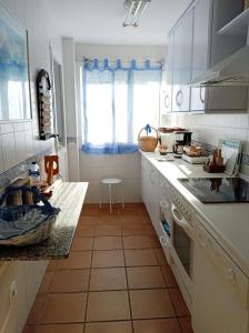 cocina con armarios blancos y suelo de baldosa en Costa Ballena Torresalada 1, en Costa Ballena