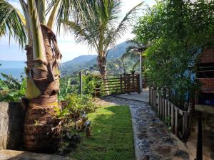 einen Garten mit Palmen und dem Meer im Hintergrund in der Unterkunft Tranquilidade e vista privilegiada in Ilhabela