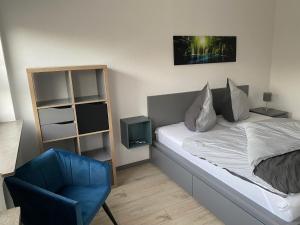 sypialnia z łóżkiem i niebieskim krzesłem w obiekcie Kassel-Appart w mieście Kassel