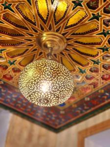 un lustre en or suspendu au plafond dans l'établissement Riad Dar Kassim, à Fès