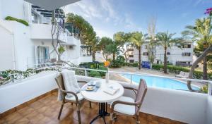a balcony with a table and chairs and a swimming pool at Apartamentos Los Tilos in Paguera