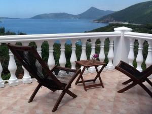 two chairs and a table on a balcony overlooking the water at Villa Mirista in Lustica