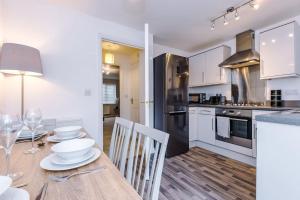 a kitchen with a wooden table and a kitchen with white cabinets at Lovely three bed home Manchester in Heywood