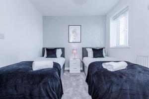 1 dormitorio con 2 camas y ventana en Lovely three bed home Manchester, en Heywood