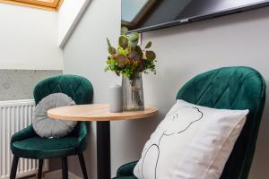 a table and two green chairs with a pillow at Felicjanek 15 - by Upstairs in Krakow +265 photos