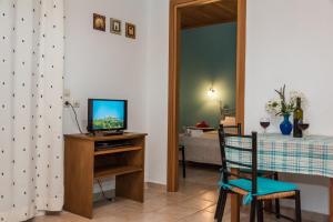 sala de estar con TV y mesa con silla en Nemorosa Holiday Houses, en Méson Yerakaríon