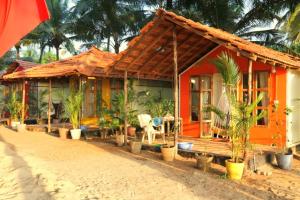 uma casa na praia com palmeiras em frente em Kranti Yoga Tradition - Beach Resort em Patnem