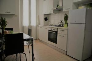 eine Küche mit weißen Geräten, einem Tisch und einem Tisch in der Unterkunft Home & Breakfast La Madonnina 013136-CNI-00001 in Lurago D'Erba 