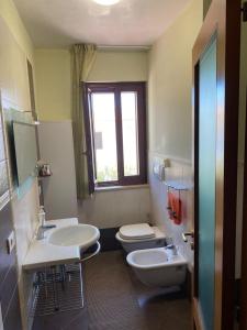 een badkamer met 2 wastafels, een toilet en een raam bij Casa Vacanze Rinaldi in Mattinata