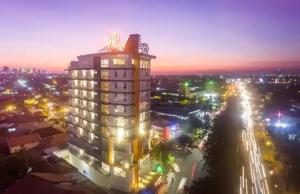 Un palazzo alto di notte con una città di Great Diponegoro Hotel Surabaya a Surabaya