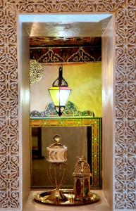 a mirror with a lamp and a lantern in front of it at Riad Dar Kassim in Fès