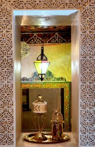 a mirror with a lamp and a lantern in front of it at Riad Dar Kassim in Fez