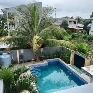 a swimming pool in a yard with a palm tree at The Balbina House in Labuan Bajo