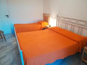 2 camas en una habitación con sábanas de color naranja en Le Querce Santa Cesarea Terme, en Santa Cesarea Terme