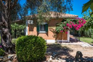 una casa con flores rosas delante de ella en Nemorosa Holiday Houses en Méson Yerakaríon