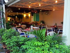 un restaurante con mesas, sillas y plantas en Paradise Inn en Karon