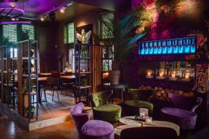 ein Restaurant mit lila Stühlen und Tischen und einer Bar in der Unterkunft Hotel De Schout in Denekamp