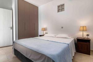 a white bedroom with a large bed and two lamps at SUNNY HOUSE IN MAKRY GIALOS in Makry Gialos