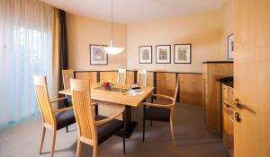 - une salle à manger avec une table et des chaises en bois dans l'établissement Dorint Charlottenhof Halle (Saale), à Halle-sur-Saale