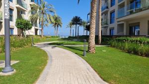 a walkway in front of a building with palm trees at Two Bedrooms Apartment at Address Residence Fujairah in Sharm