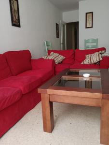 salon z czerwonymi kanapami i stolikiem kawowym w obiekcie Piso Calzada de la Infanta Tres Carabelas Sanlúcar de Barrameda w mieście Sanlúcar de Barrameda