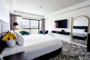 Habitación de hotel con cama grande y espejo en The Benson Hotel en Cairns