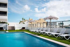 uma piscina com cadeiras e guarda-sóis no topo de um edifício em The Benson Hotel em Cairns