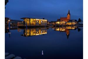 a group of boats sitting on the water at night at Hausboot Fjord Vela mit Biosauna in Barth in Barth