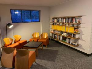 uma biblioteca com cadeiras laranja e uma estante de livros com livros em Hotel Kapellerput Heeze-Eindhoven em Heeze