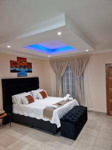 1 dormitorio con 1 cama grande y techo azul en Danrit Guesthouse - Uncapped wifi en Roodepoort