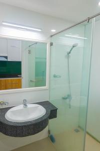 La salle de bains est pourvue d'un lavabo et d'une douche en verre. dans l'établissement Dương Hằng- Ocean Vista Sealinks, à Ấp Ngọc Hải