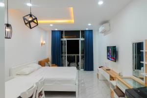 a bedroom with a white bed and blue curtains at Dương Hằng- Ocean Vista Sealinks in Ấp Ngọc Hải