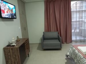 a living room with a chair and a television at Bella Luxury Suite II in Paralia Katerinis