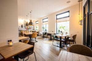 een restaurant met tafels, stoelen en ramen bij Hotel Neptunus in Egmond aan Zee