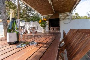 un tavolo in legno con bicchieri da vino e una bottiglia di vino di Villa can torrent a San Jose de sa Talaia