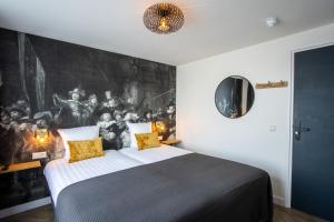 a bedroom with a large bed with a painting on the wall at Hotel Neptunus in Egmond aan Zee