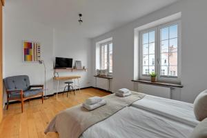 a white bedroom with a large bed and a desk at City & Old Town View Rooftop by Downtown Apartments in Gdańsk