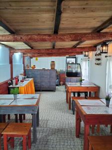 a dining room with wooden tables and a kitchen at Alojamento Raminho dos Açores in Angra do Heroísmo