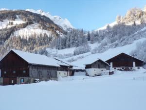 a group of barns in the snow with a mountain at Ferienwohnung Moharblick 2 in Großkirchheim